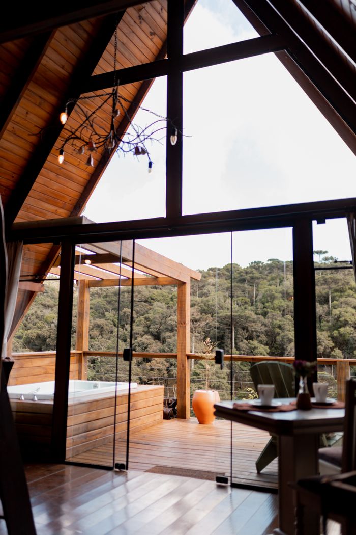gallery-4 A tranquil cabin interior with large windows and hot tub overlooking a forest.