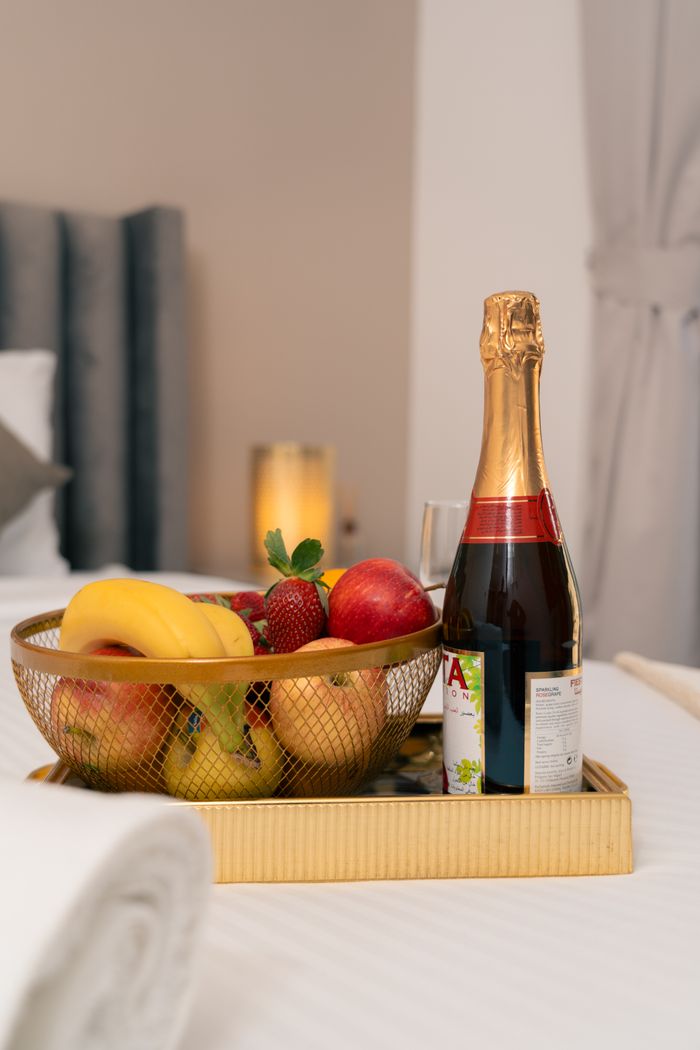 gallery-3 Elegant hotel room featuring fruit basket and champagne on a tray.