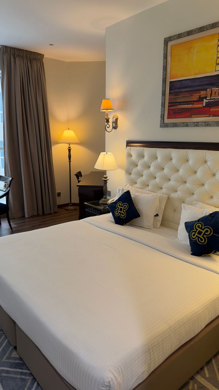 services-02 Cozy hotel room featuring a plush bed, artistic decor, warm lighting, and stylish furnishings.