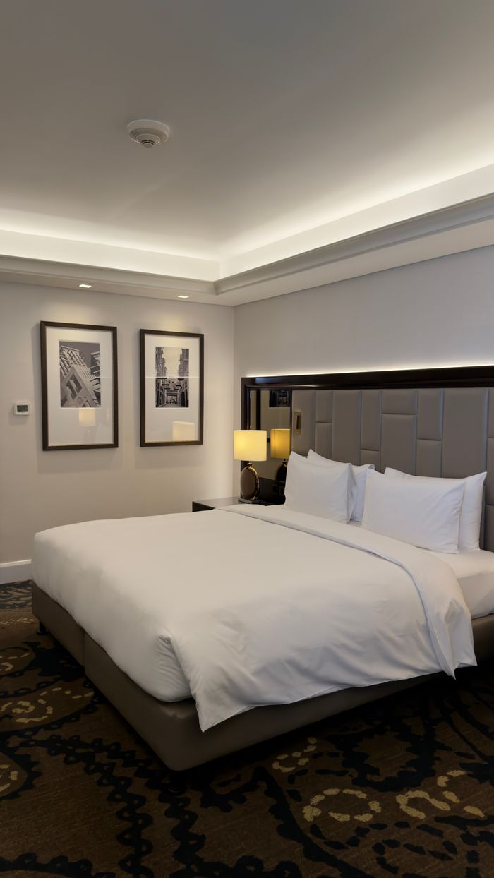 Crafting Captivating Headlines: Your awesome post title goes here Modern hotel room with luxurious bedding and stylish decor, featuring framed cityscape art.