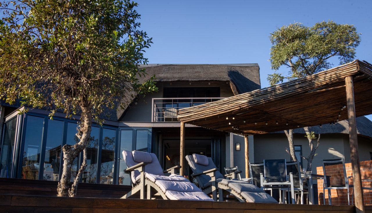 services-02 Elegant outdoor patio at a modern safari lodge with sun loungers and natural wood pergola.